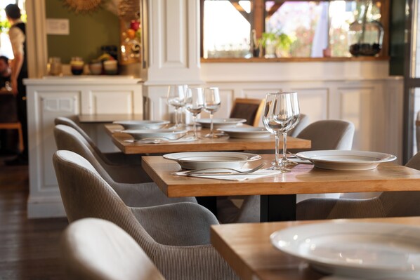Interior de restaurante con mesas y sillas de madera, y platos vacíos.
