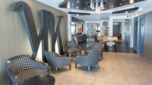 A modern lobby with patterned chairs, a reception desk, and a large abstract wall art piece.