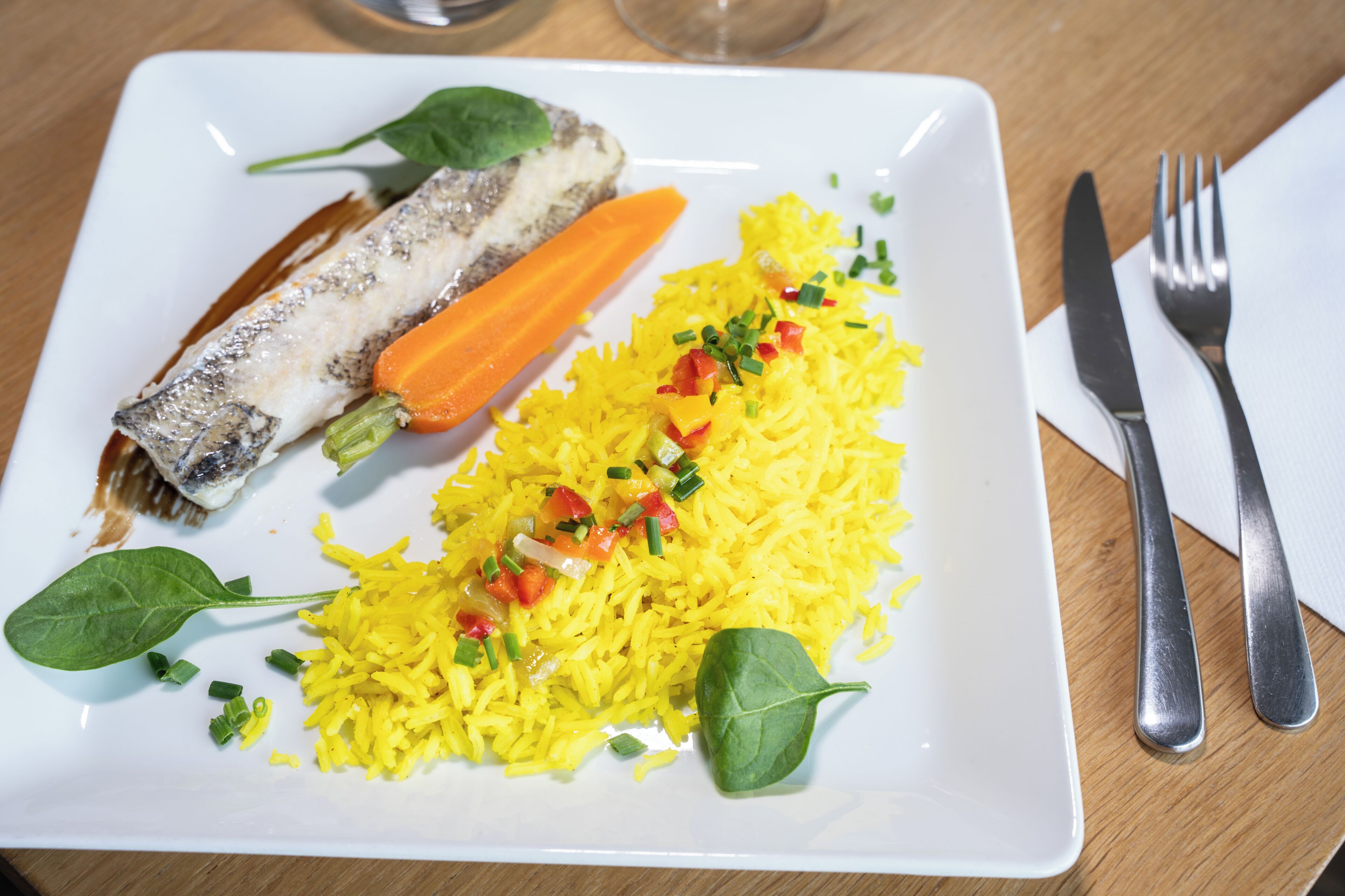 Un plato de comida con arroz, verduras y pescado.