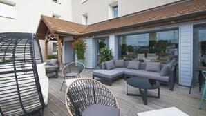 An outdoor patio with a grey sectional sofa, wicker chairs, and a round table.