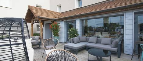An outdoor patio with a grey sectional sofa, wicker chairs, and a round table.