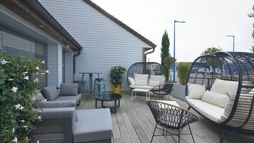An outdoor patio with a grey sofa, a round table, and a hanging chair.