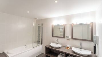 Une salle de bain moderne avec une baignoire, deux lavabos et un grand miroir.