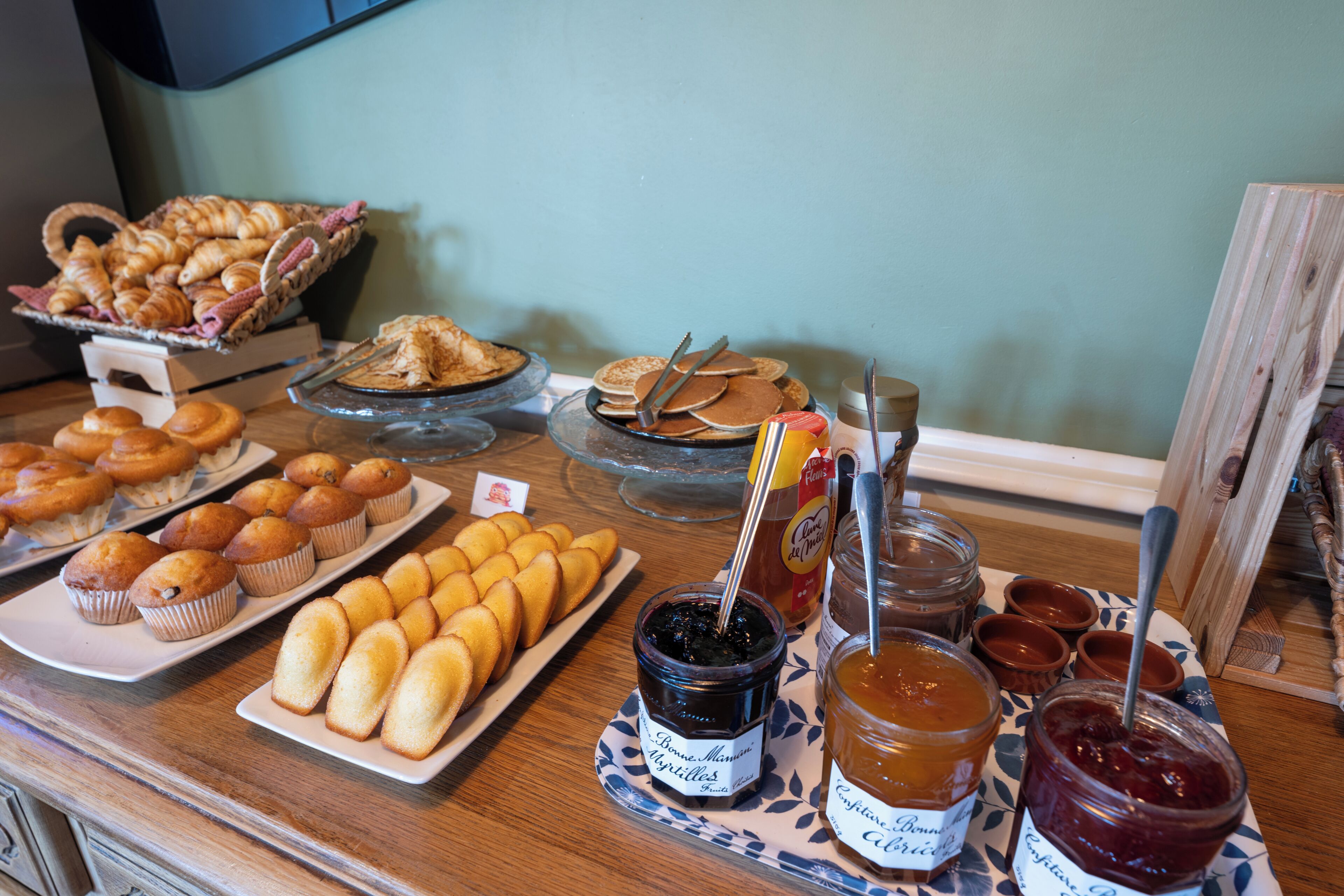 Uma mesa de buffet com pães, bolinhos e geleias.