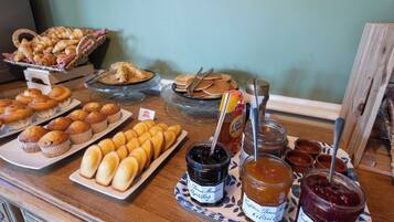Uma mesa de buffet com pães, bolinhos e geleias.