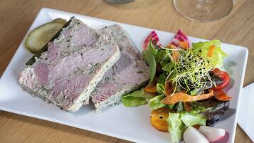 Ein weißer, rechteckiger Teller mit geschnittenem Fleisch und einem gemischten Gemüsesalat.