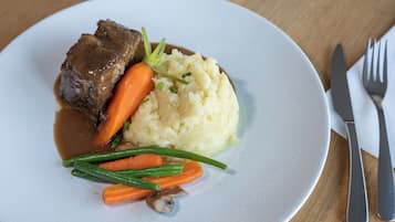 A plate with beef, mashed potatoes, carrots, and green beans.