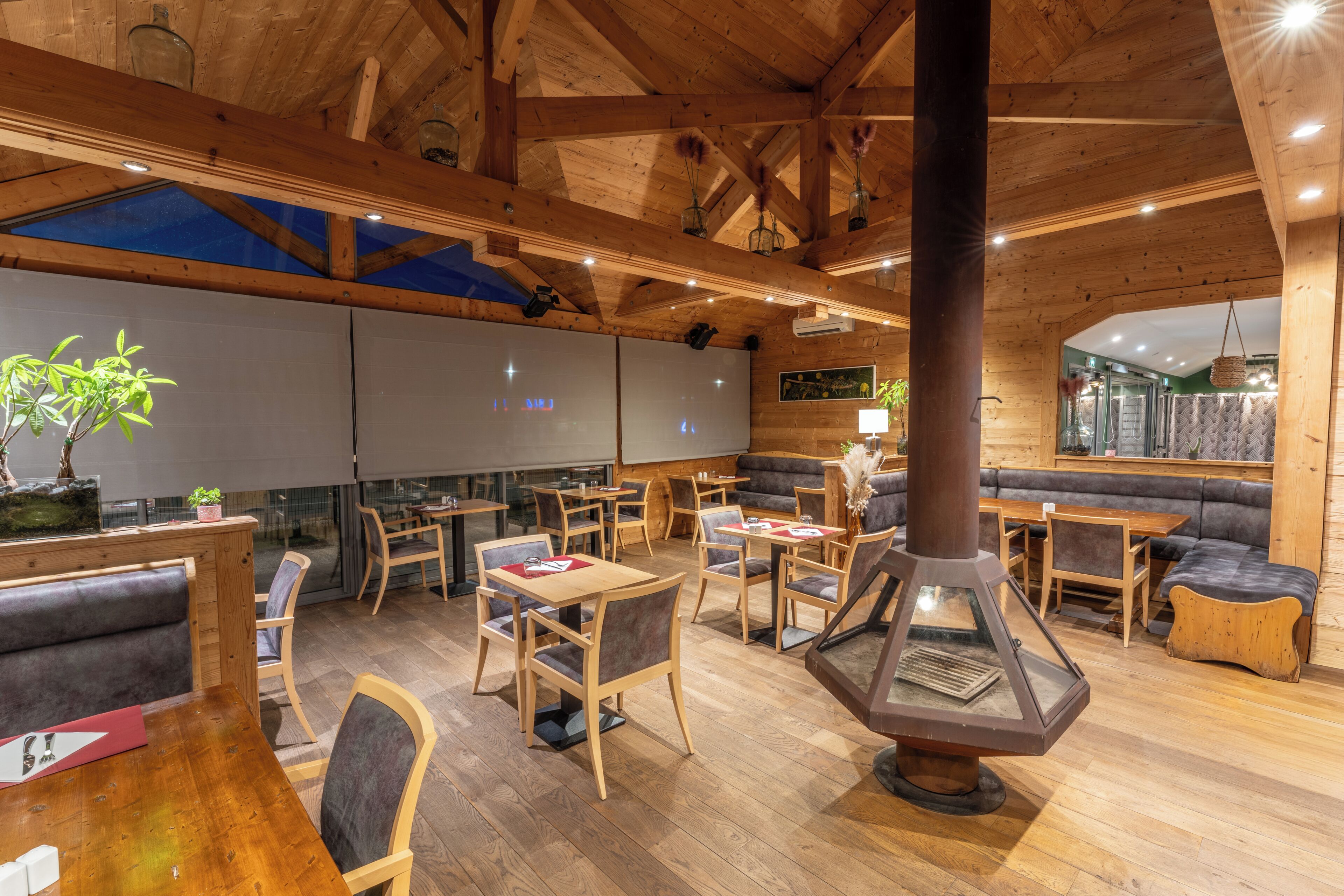 A wooden interior with tables, chairs, a fireplace, and a seating area.