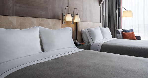 A hotel room with two beds, a nightstand, and a lamp.