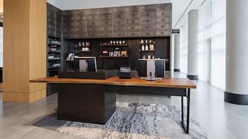 Un moderno hall de hotel con una recepción, una barra de café y una exhibición de servicios.
