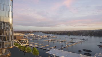 Marina com barcos atracados, um edifício de vidro e paisagem urbana ao fundo.
