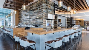 Eine moderne Bar mit einer langen Theke, mehreren Barhocker und hängenden Pendelleuchten.