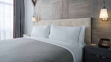 A hotel room with a large bed, a bedside table with a lamp, and a telephone.