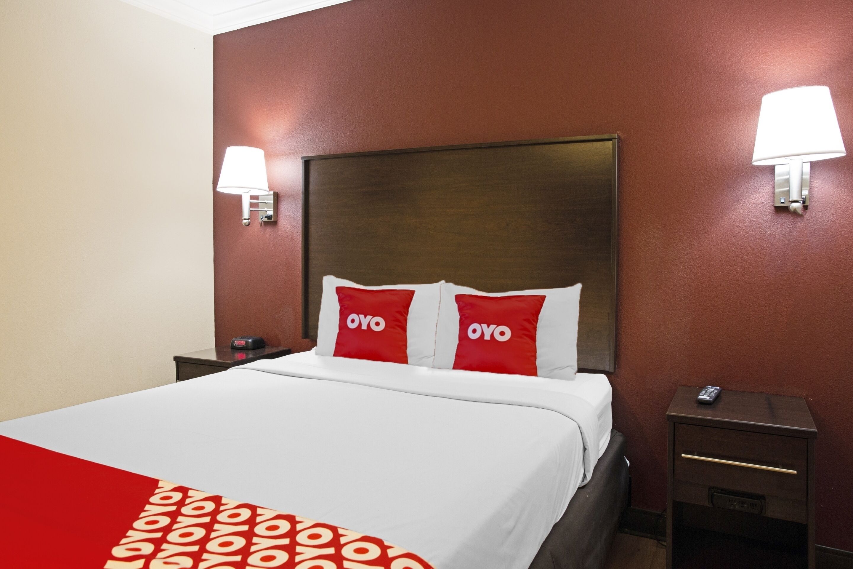 A hotel room with a large bed, two bedside tables, and two wall-mounted lamps.