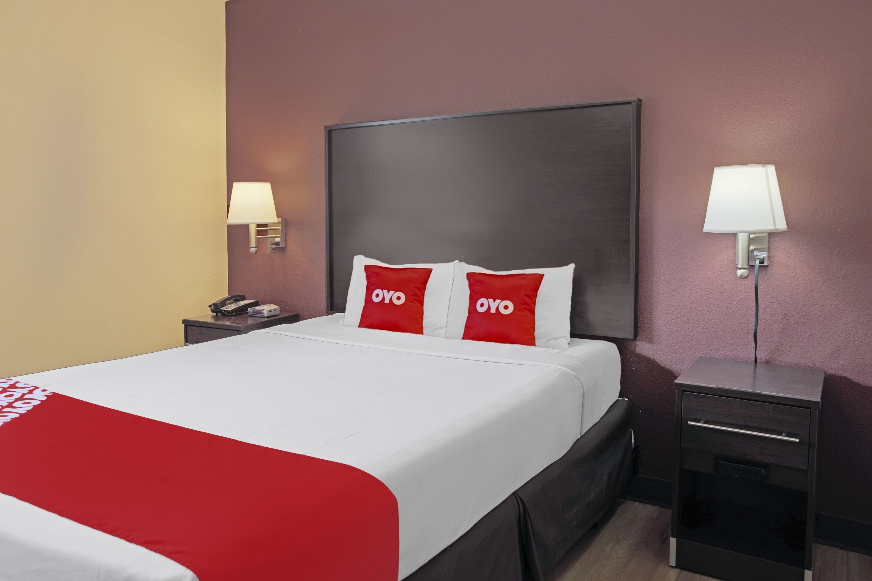 A hotel room with a large bed, two bedside tables, and two wall-mounted lamps.