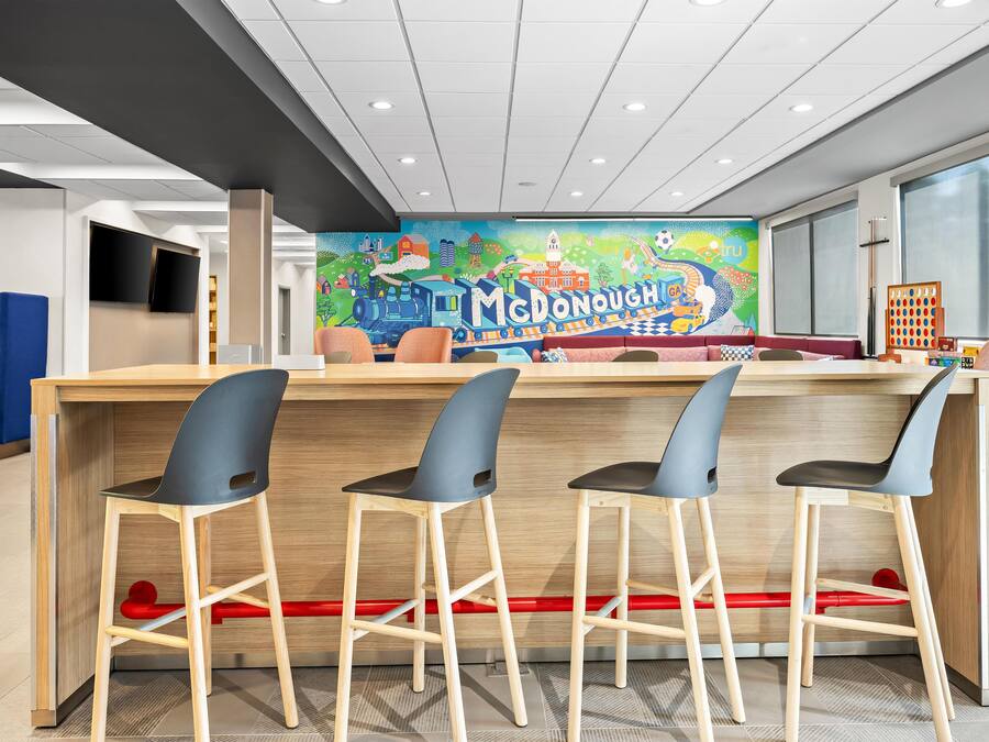Un área de juegos infantiles con un mural colorido, una barra con taburetes y un sofá azul.