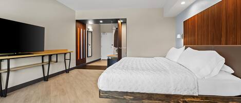 Una habitación de hotel moderna con una cama grande, un escritorio y una televisión.