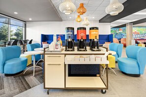 Un caffè moderno con posti a sedere blu, una macchina per caffè e un distributore d'acqua.