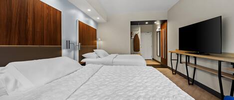 Una habitación de hotel con dos camas, televisión, escritorio y espejo.