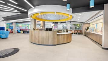 A modern reception area with a central desk, seating, and a colorful mural in the background.