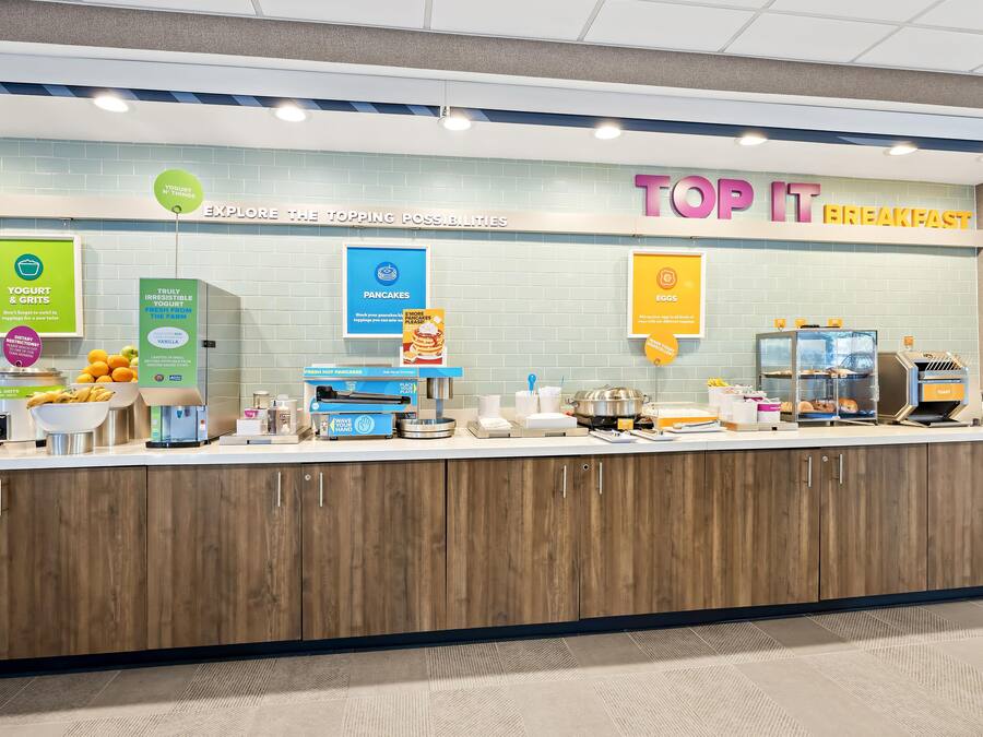 A breakfast station with yogurt, grits, pancakes, and eggs.