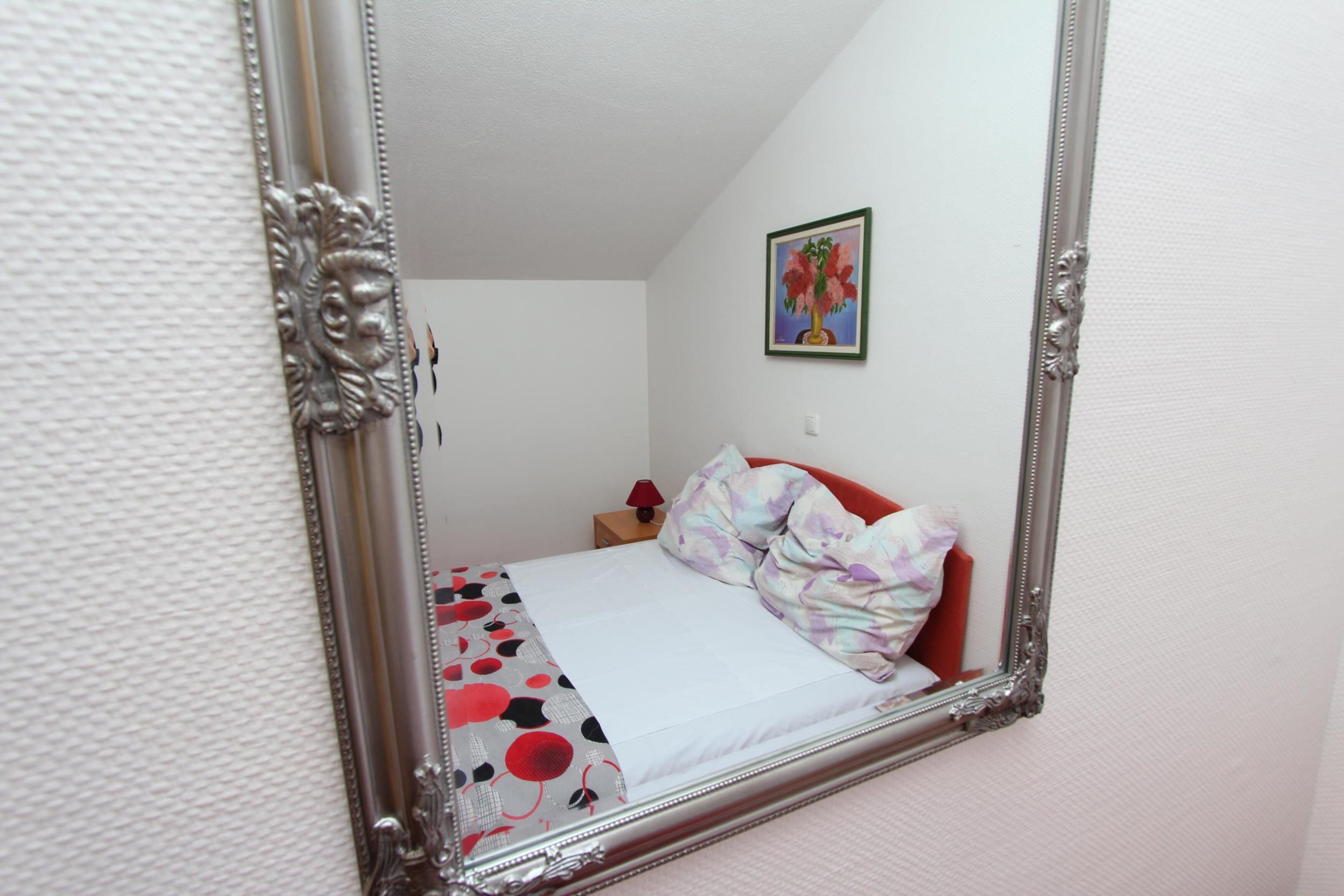 A bedroom with a bed, a nightstand, a lamp, and a painting on the wall.