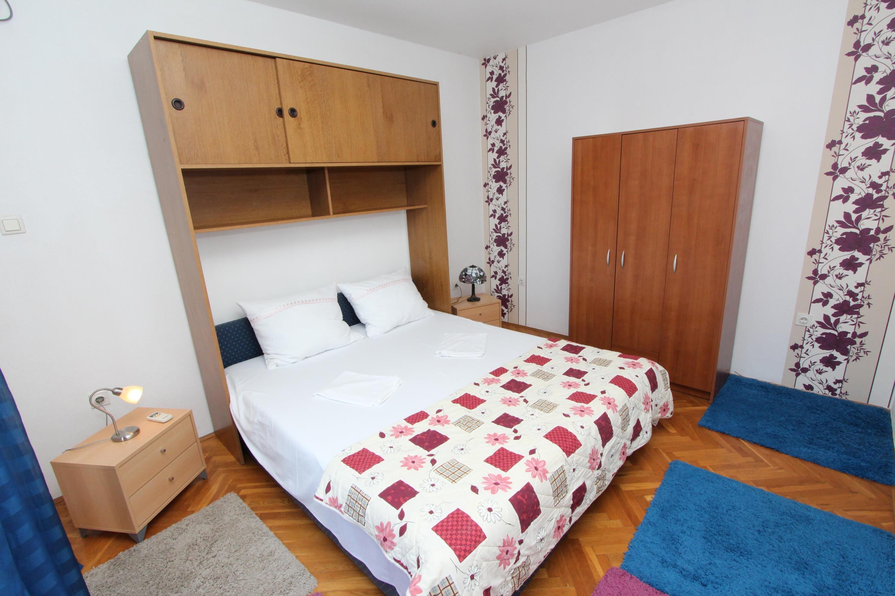 Une chambre à coucher comprenant un lit, une armoire en bois, une table de chevet et un motif floral sur le mur.