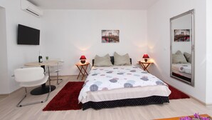 A modern bedroom with a bed, two bedside tables with lamps, a chair, a TV mounted on the wall, and two framed pictures. - Rooms and apartments Sally (Rovinj)