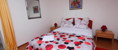 Una camera da letto con un letto, un comodino, una lampada, uno specchio e un quadro appeso al muro.