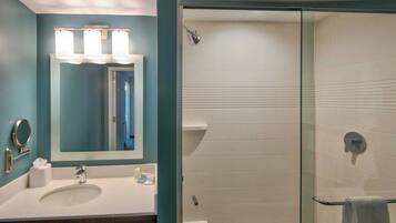 A bathroom with a sink, mirror, and shower.
