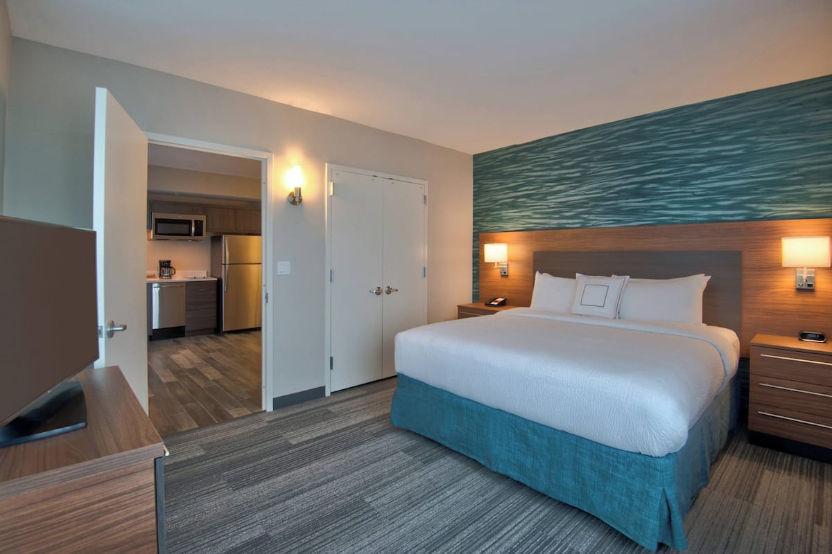 Une chambre d’hôtel comprenant un lit, des tables de chevet, un bureau, un four à micro-ondes, un réfrigérateur et un petit coin cuisine.