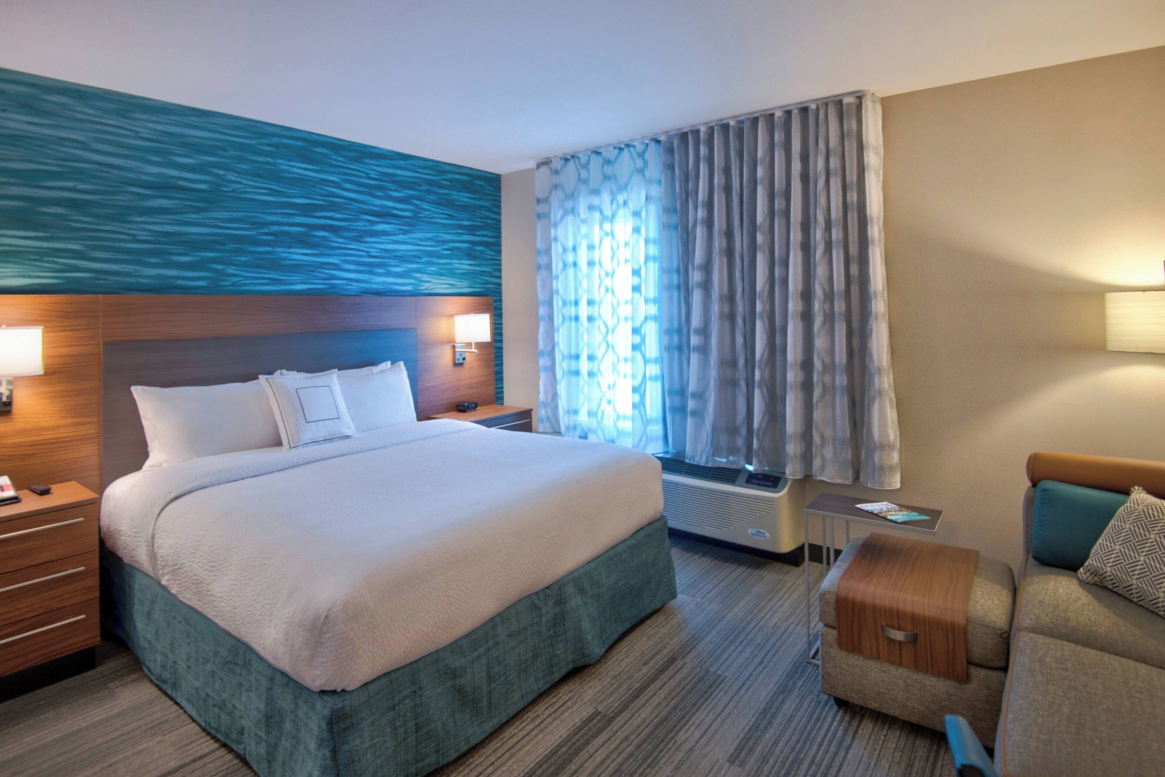 Een hotelkamer met een groot bed, een bureau, een stoel en een raam met gordijnen.