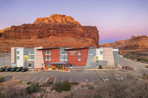 A hotel with a modern design, a parking lot, and a large rock formation in the background. - SpringHill Suites by Marriott Moab (Moab)