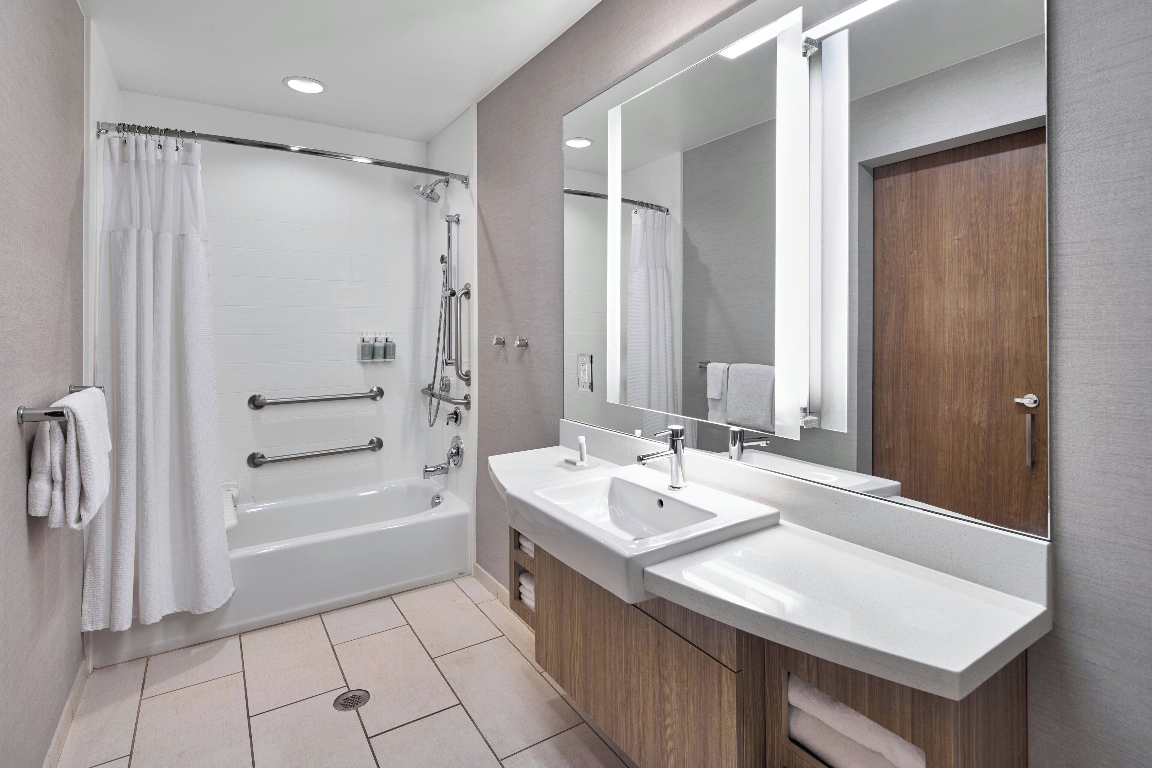 Un baño moderno con bañera, dos lavabos, un espejo grande y ducha.