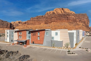 A modern hotel with a prominent brick facade, a parking lot, and a mountainous backdrop. - SpringHill Suites by Marriott Moab (Moab)
