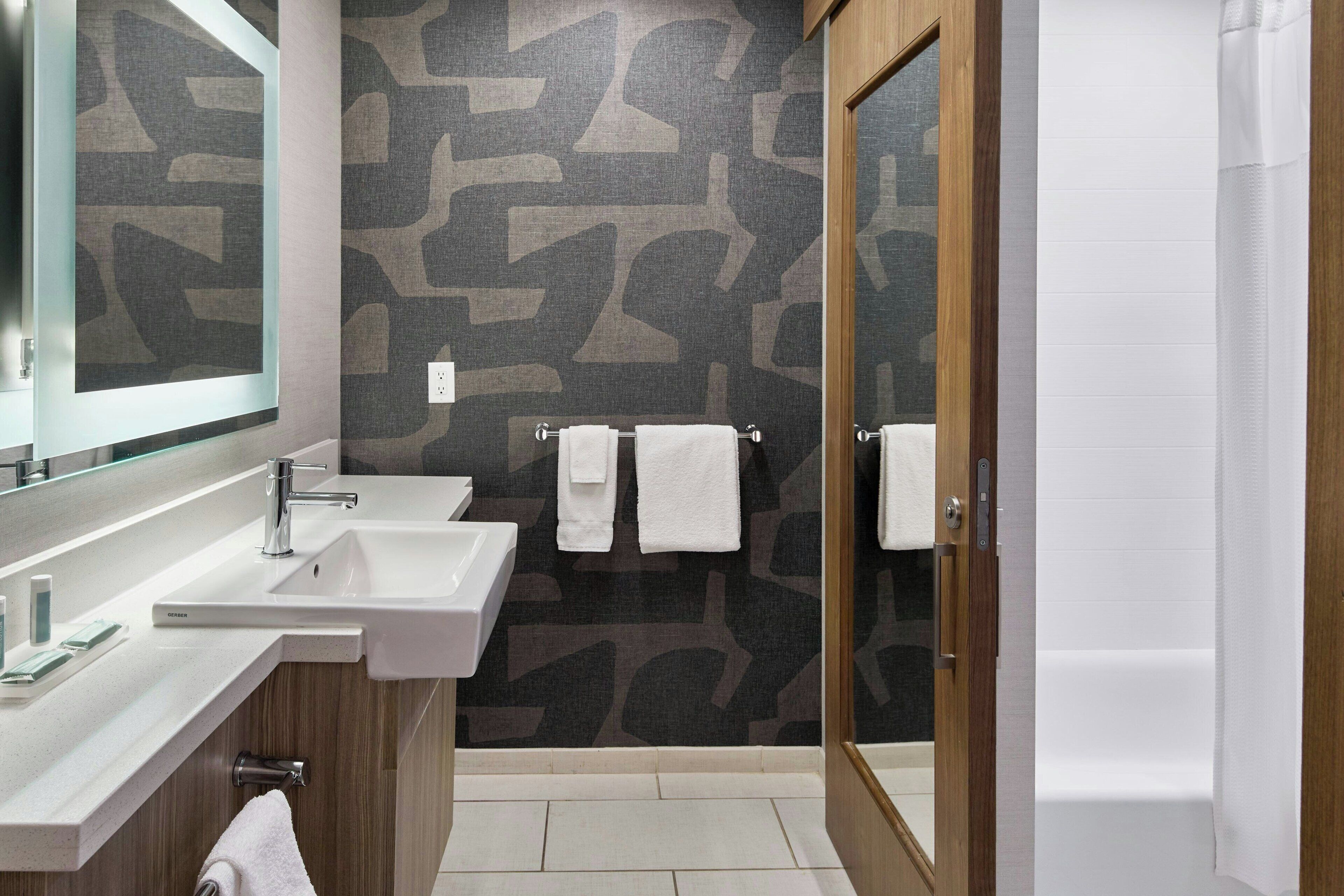 Un baño moderno con dos lavamanos, un espejo y una zona de ducha.