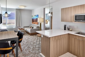 A modern hotel room with a kitchen, dining area, and a large window with a view. - SpringHill Suites by Marriott Moab (Moab)