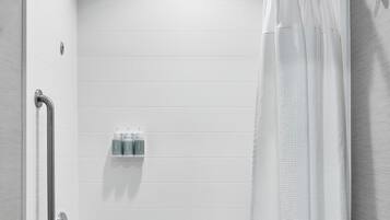 Un baño moderno con una bañera blanca, un cortinón de ducha y un pasamanos.