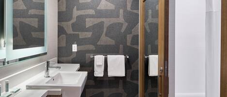 A modern bathroom with two sinks, a mirror, and a shower area.