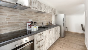 A modern kitchen with a stone backsplash, stainless steel appliances, and wooden cabinets.