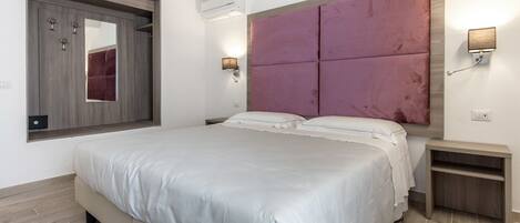 Un dormitorio moderno con una cama grande, un armario empotrado, un espejo y un aplique de pared.