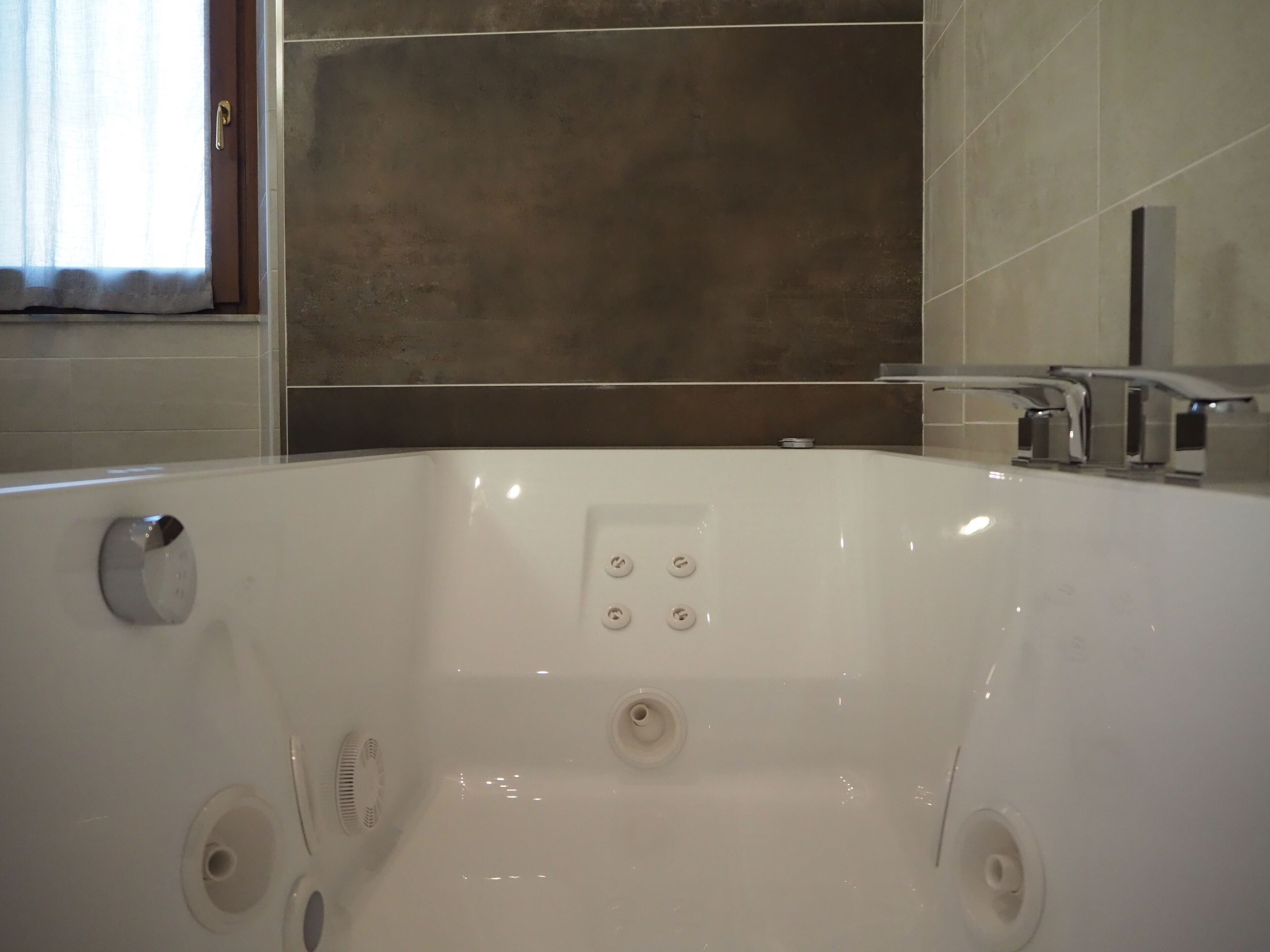 Ein modernes Badezimmer mit einer großzügigen weißen Badewanne, einer Duschkabine und einem WC.