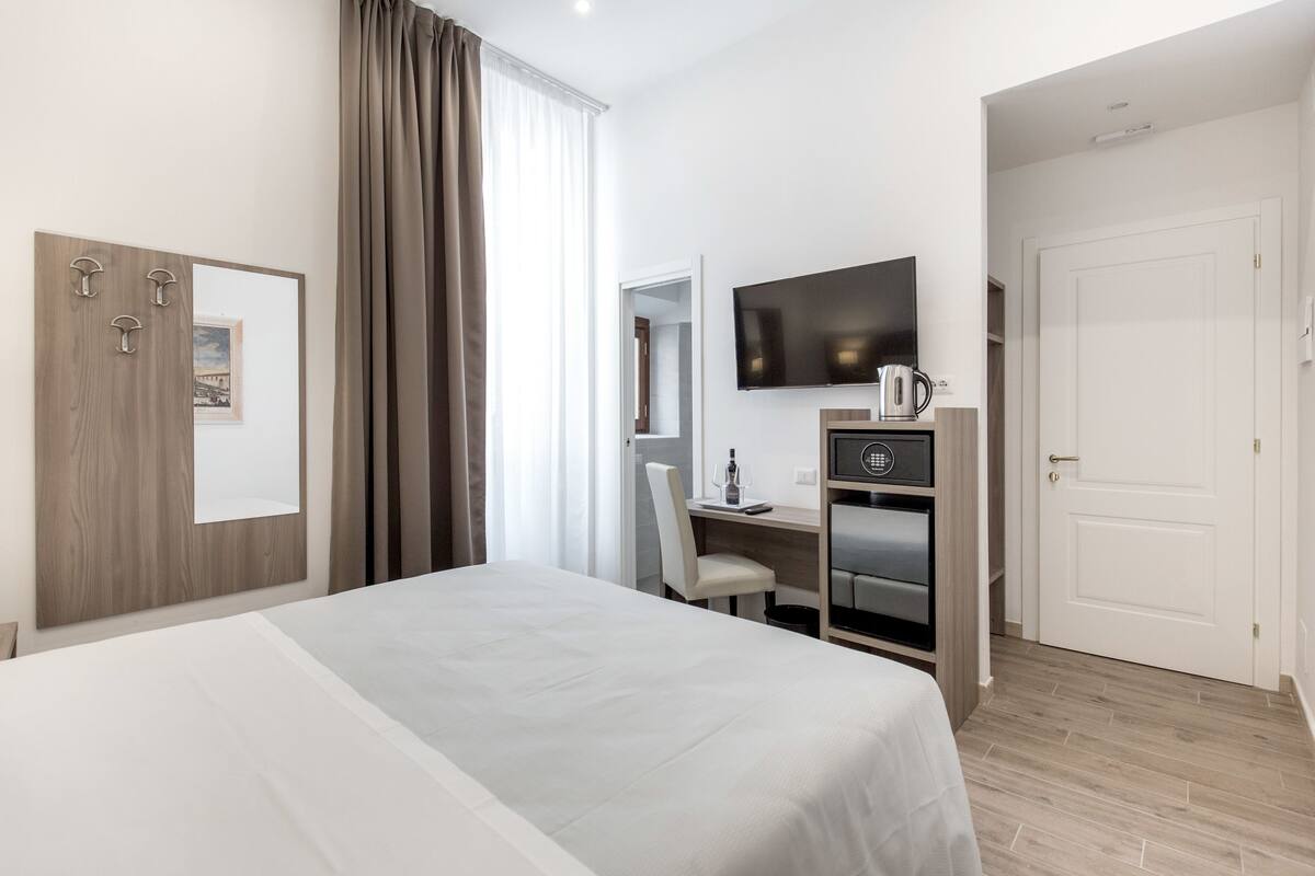Une chambre d’hôtel comprenant un lit, un bureau avec une chaise, une télévision et un minibar.