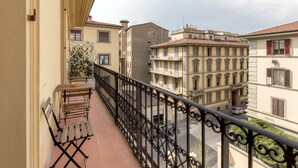A balcony with a wrought iron railing, a wooden bench, and a potted plant.