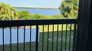 A balcony with a view of a body of water and greenery.