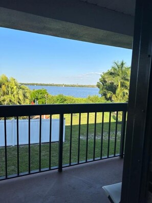 A balcony with a view of a body of water and greenery.