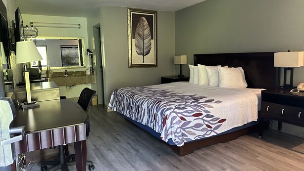 Une chambre d’hôtel équipée d’un lit, d’un bureau, d’une chaise et d’un grand miroir.