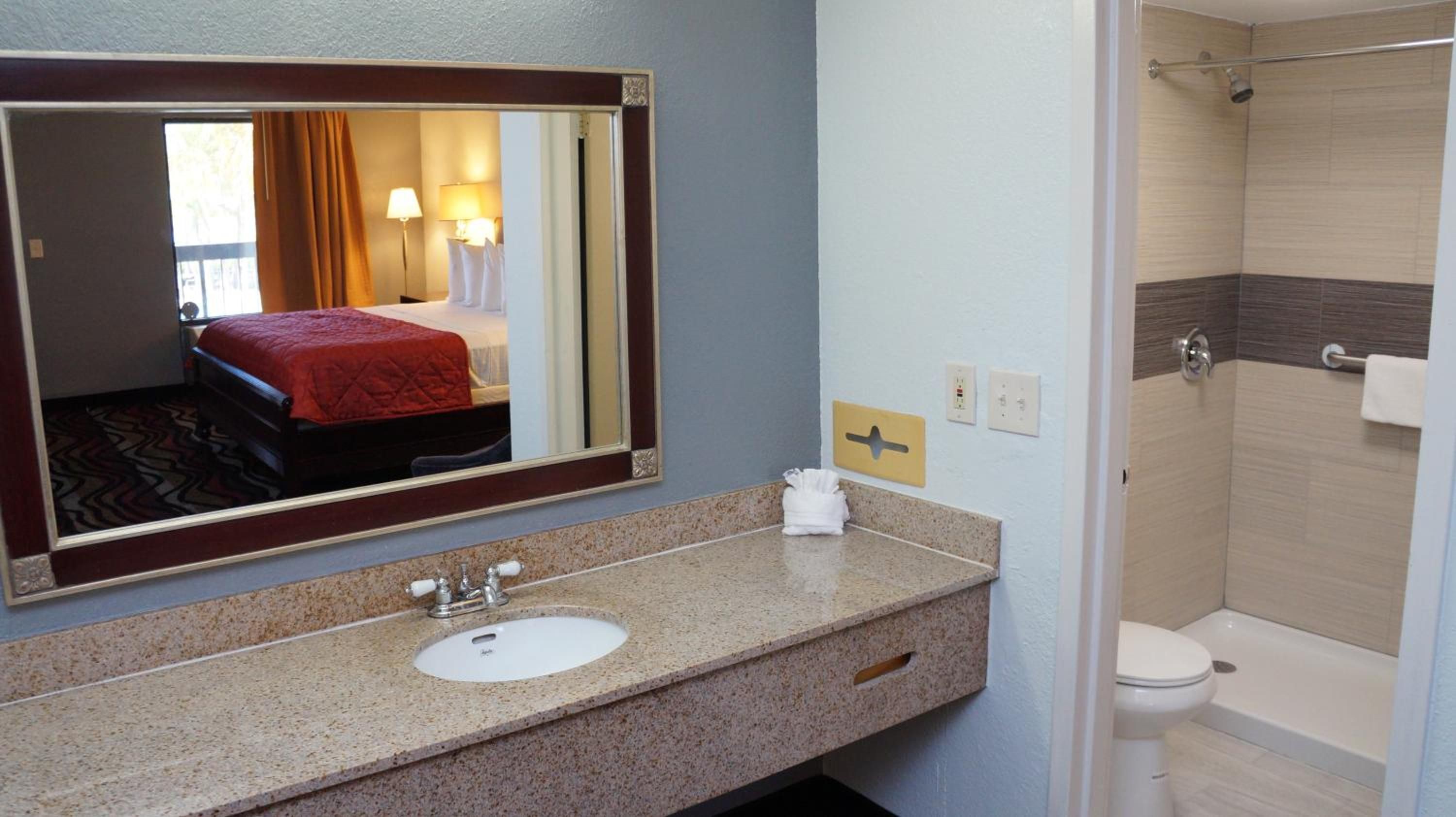 Un baño de hotel con lavamanos, espejo y ducha.