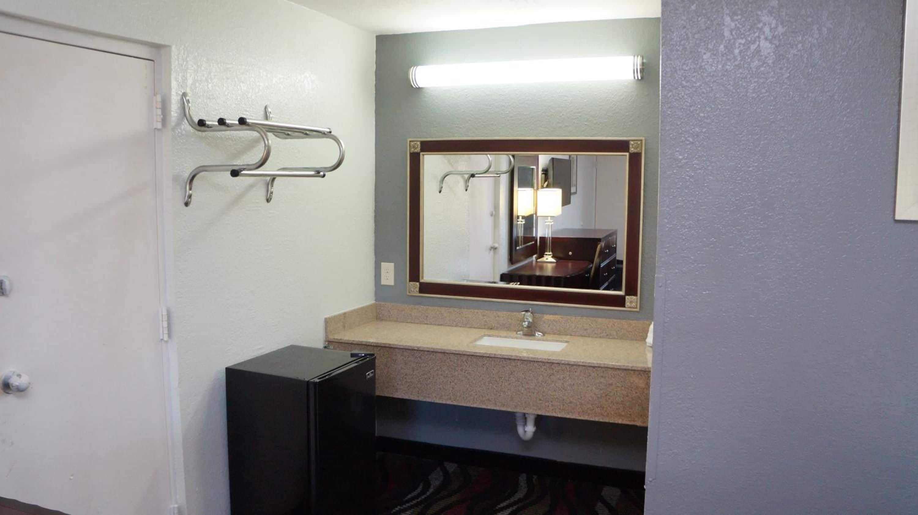 Une salle de bain équipée d’un lavabo, d’un miroir, d’un porte-serviettes et d’une petite armoire noire.