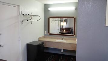 Une salle de bain équipée d’un lavabo, d’un miroir, d’un porte-serviettes et d’une petite armoire noire.